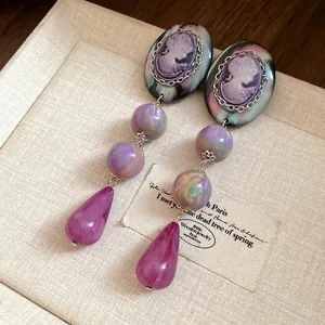 Close-up of vintage cameo earrings with purple marble resin beads and teardrop drops.