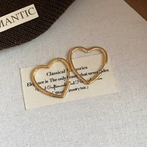 Close-up of minimalist gold-plated heart-shaped hoop earrings on fabric background