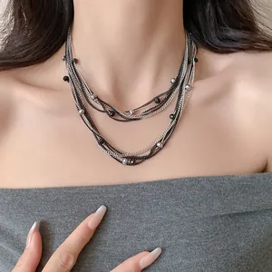 Dettaglio di una collana multistrato con perline argento e nero su modella.