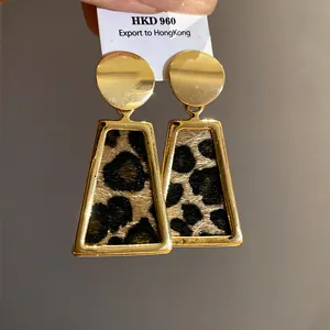 Detailed view of gold-tone leopard print trapezoid earrings with textured animal pattern