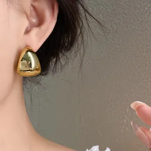 Vista detallada de elegantes pendientes geométricos dorados con un acabado brillante