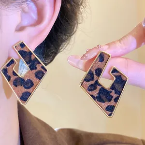 Close-up detail of leopard print hollow geometric earrings with golden metal borders.