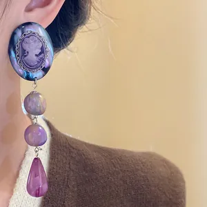 Close-up of vintage purple cameo earrings with teardrop pendant worn by model