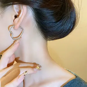 Macro view of elegant minimalist silver-tone heart-shaped hoop earrings worn by a model
