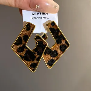 Detailed view of geometric hollow leopard print earrings with gold-toned metal frame