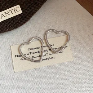 Macro view of minimalist silver heart-shaped hoop earrings with a polished finish