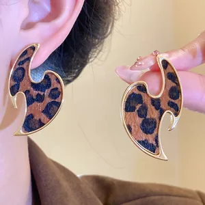 Macro view of unique leopard print earrings featuring a stylish gold-tone metallic frame