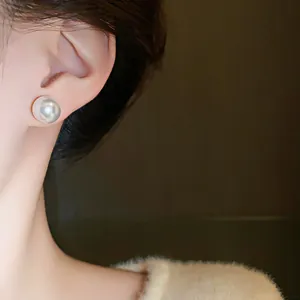 Primer plano de elegantes pendientes de perla blanca en una oreja, estilo francés