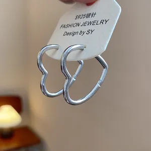 Detail showing polished silver heart-shaped hoop earrings on white display card