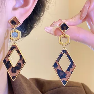 Close-up of elegant leopard print geometric dangle earrings with gold hollow design.