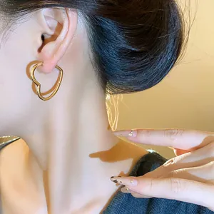 Elegant gold heart-shaped hoop earrings shown in a close-up detail shot on model.