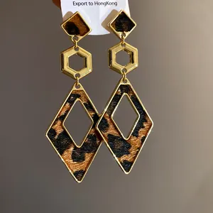 Detailed close-up showing gold-toned leopard print geometric hollow dangle earrings on display card
