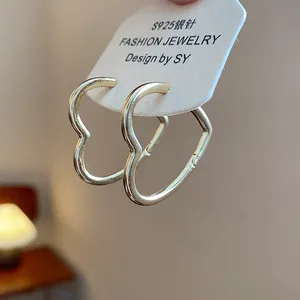 Detailed close-up of heart-shaped gold glossy hoop earrings with S925 silver needles