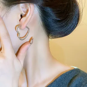 Close-up showing the elegant wearing effect of the silver heart-shaped hoop earring