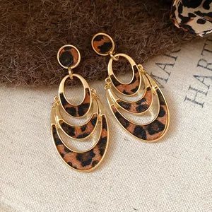 Close-up of elegant gold tiered oval earrings with fuzzy leopard print pattern texture