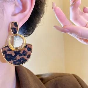 Close-up view of stylish leopard print earrings with gold hollow circle design on ear.
