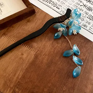 Close-up view of a handcrafted Chinese style hair stick featuring blue flowers and tassels