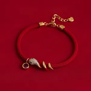 Detailansicht eines roten Seilarmbands mit vergoldetem Schlangenanhänger und Zirkonia