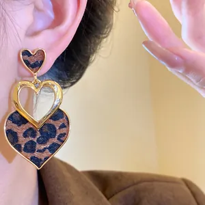 Close-up view of elegant triple heart dangle earrings featuring leopard print and gold trim