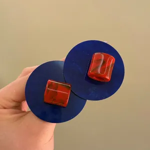 Macro detail of retro oversized blue and red marbled acrylic round stud earrings.