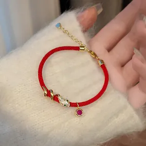 Detailansicht eines roten Seilarmbands mit vergoldetem Zirkonia Schlangenanhänger und Edelstein
