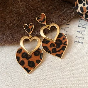 Detailed macro view of leopard print heart earrings featuring an elegant gold hollow design