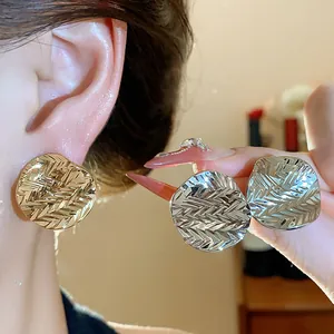 Close-up detail showing the unique textured finish of these round gold and silver earrings