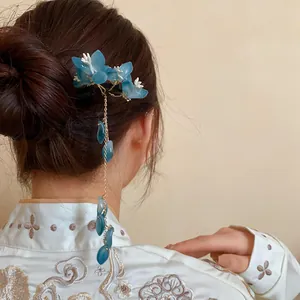 Detail view of a blue flower tassel hair stick worn in a classic bun on an Asian model