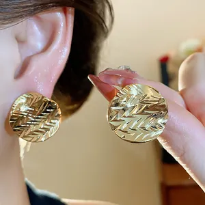Close-up of 18k gold plated round stud earrings with textured crumpled design.