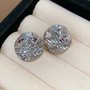 Macro view of silver textured round stud earrings with unique wrinkled surface pattern