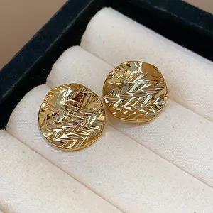 Detail view of 18k gold plated round stud earrings with unique wrinkled textured surface