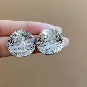 Close-up of textured round metal stud earrings with a crumpled finish in silver tone.