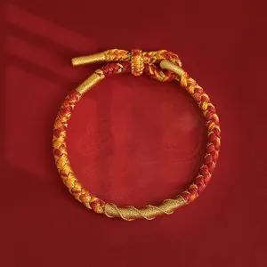 Nahaufnahme eines handgewebten rot-goldenen Armbands mit Spiraleffekt