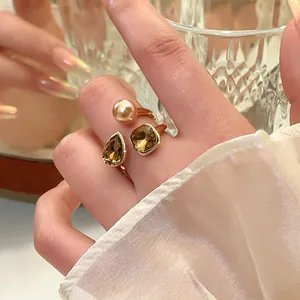 Nahaufnahme eines eleganten vergoldeten offenen Rings mit Perle und braunen Kristallen.