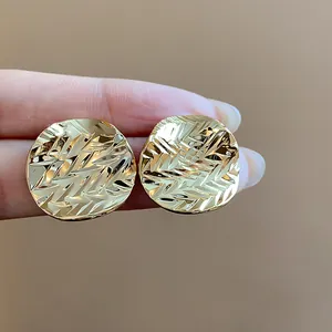 Macro view of textured 18k gold plated round stud earrings showcasing crinkled detail