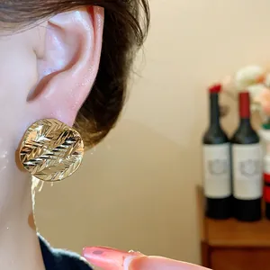 Close-up detail of gold-plated wrinkled round stud earrings with a textured surface