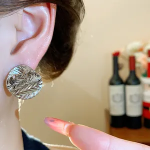 Detailed close-up view of a minimalist silver textured round stud earring on an ear