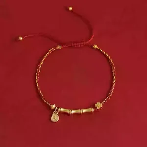 Detailansicht des handgefertigten geflochtenen roten und goldenen Armbands mit Bambusanhänger