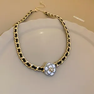 Elegant detail of French style gold interwoven chain necklace with camellia flower pendant