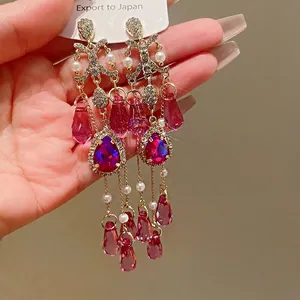 Eleganti orecchini vintage in stile corte con cristalli rosa e perle tenuti in mano