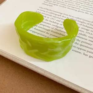 Dettaglio ravvicinato di un bracciale in acrilico verde lime con trama ondulata unica