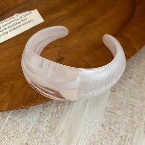 Primo piano di un elegante bracciale rigido in acrilico marmorizzato bianco dal design