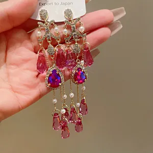 Dettaglio di orecchini vintage con nappe, cristalli magenta e perle eleganti