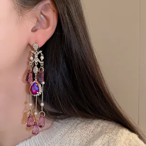 Primo piano di eleganti orecchini a nappa in cristallo viola con strass su una modella.