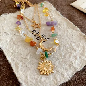 Detail shot of the gold-tone layered necklace with sun, moon, star charms and colorful stones.