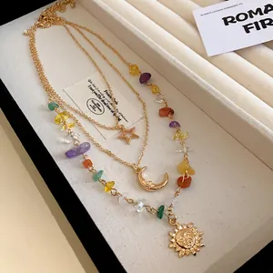 Detail view of multi-layer gold necklace with sun, moon, and star pendants and colorful beads