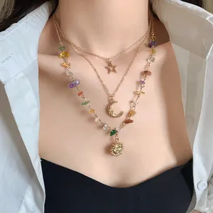 Close-up detail of a bohemian triple-layered necklace with sun moon and star charms.