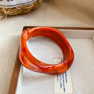 Bracciale rigido minimalista in acrilico arancione con motivo a spirale marmorea bianca