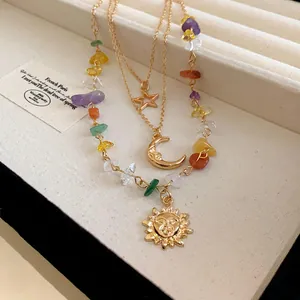 Detailed close-up of layered necklace featuring celestial pendants and multi-color stones