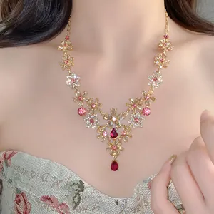 Detailed view of a vintage floral necklace with pink rhinestones and red teardrop pendants.